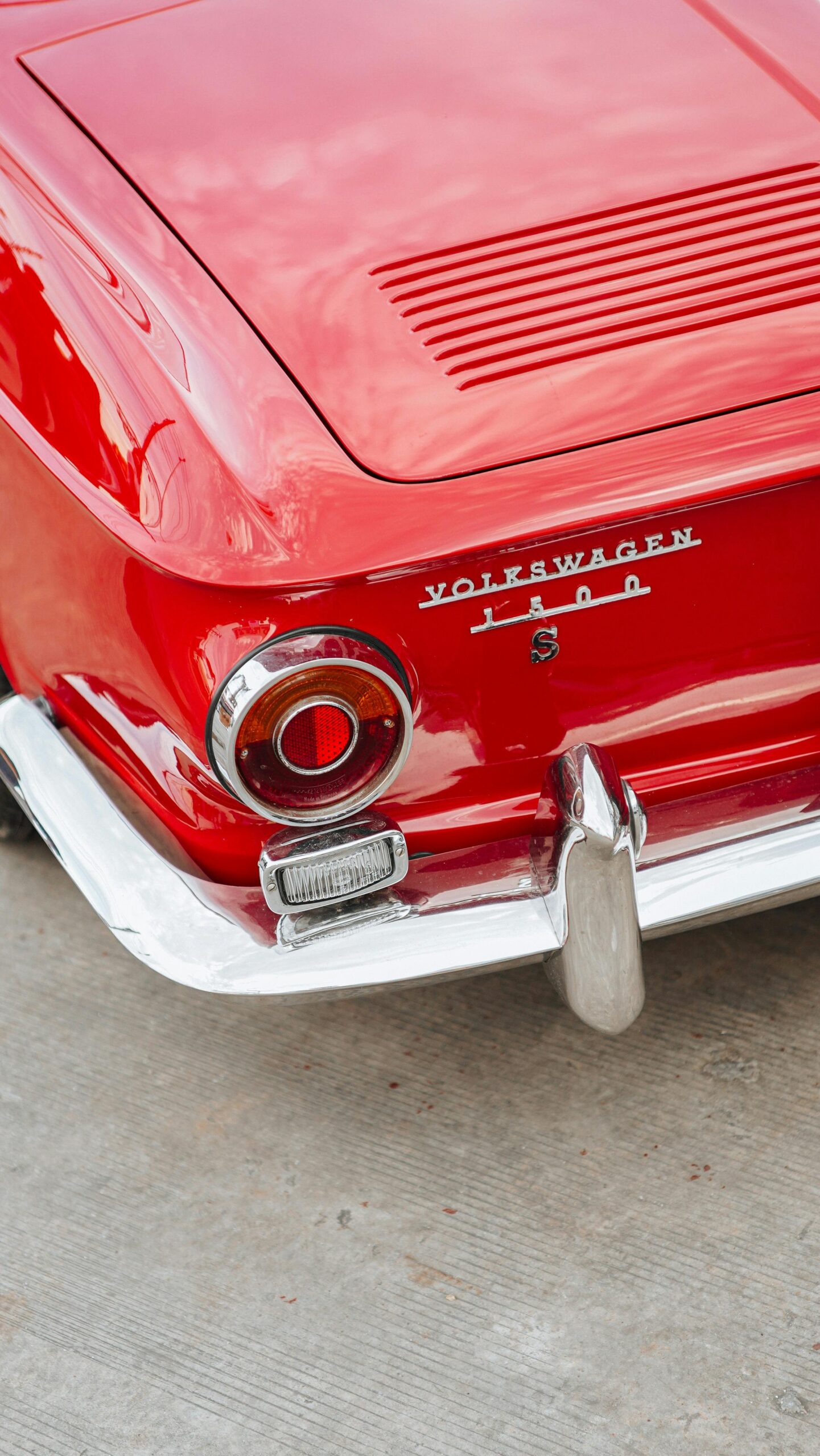 Close-up of a classic red Volkswagen 1500 with chrome details, showing rear light and exhaust pipe.